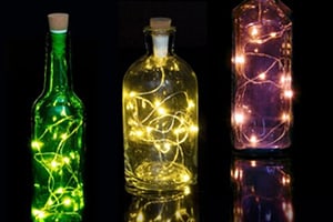 String lights attached to a cork and inserted in to colourful glass bottles.