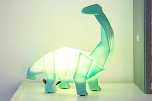 An origami-style Diplodocus dinosaur shaped novelty lamp, glowing a light green colour.