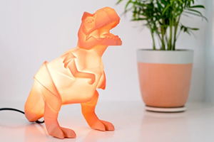 An origami-style T-Rex dinosaur shaped novelty lamp, glowing a light orange colour.